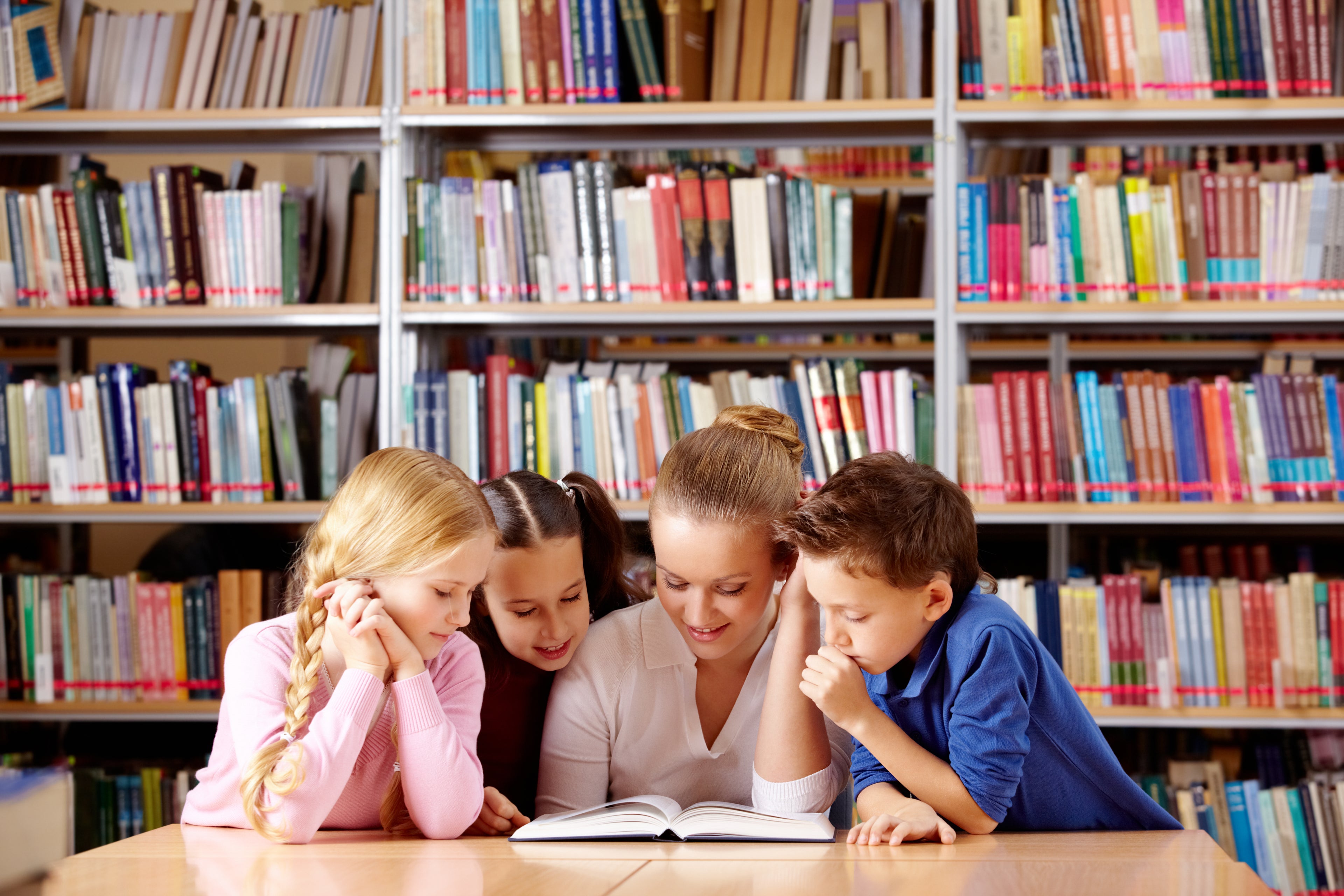 Image of an adult woman reading a book with three children.